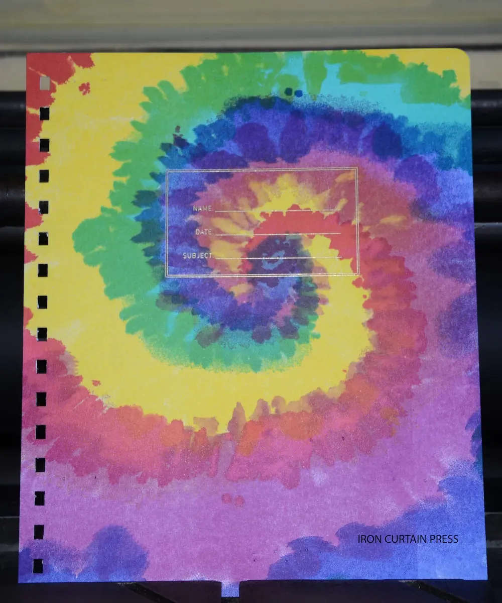 A tie-dye letterpress notebook cover in saturated rainbow inks