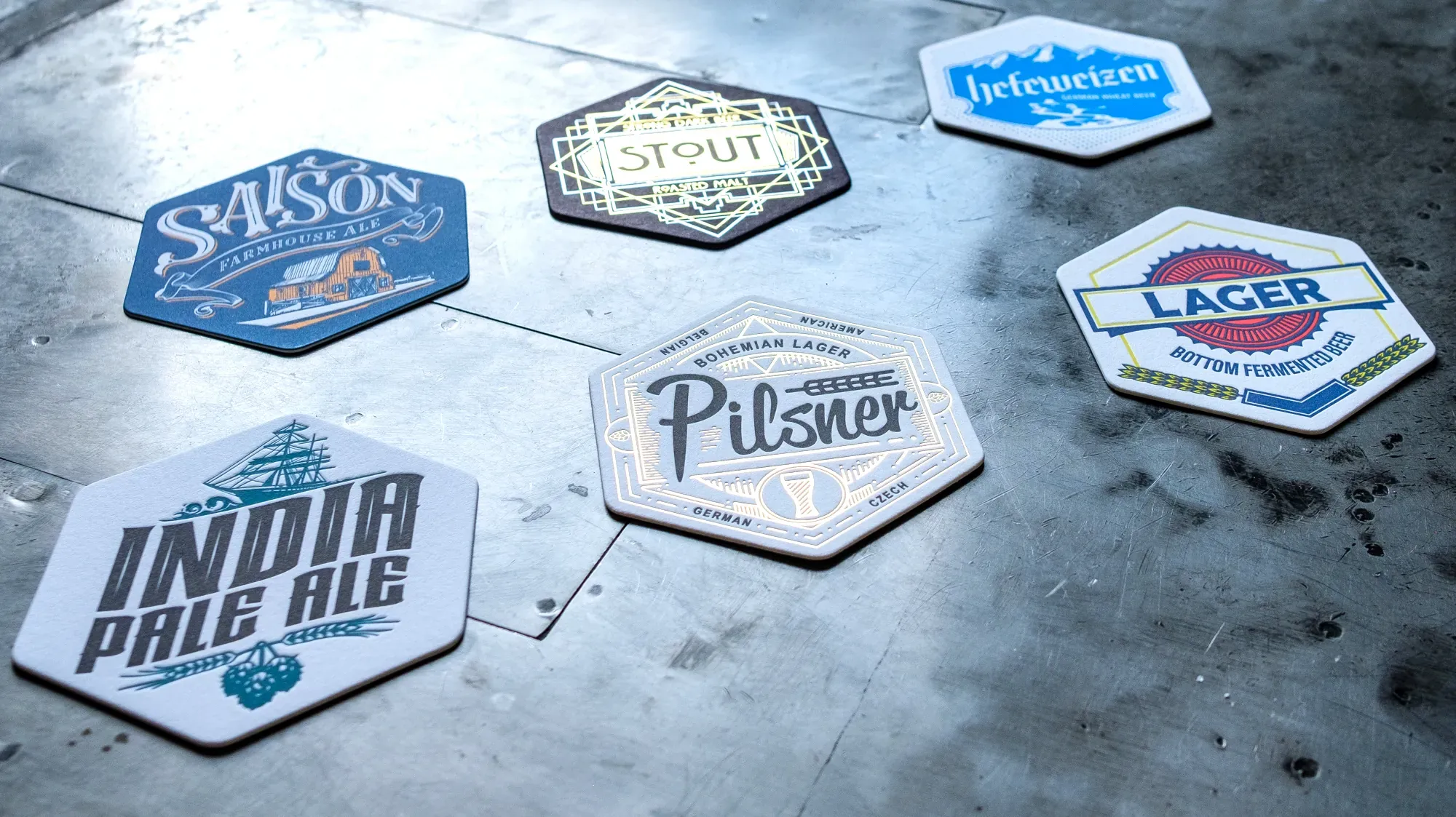 Letterpress printed beer coasters in several inks arranged on a steel press bed