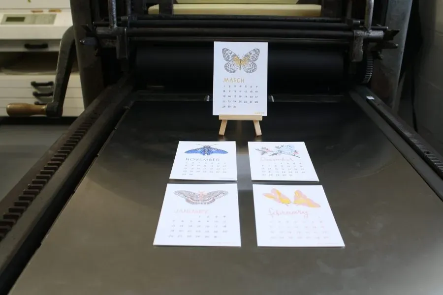 Letterpress butterfly calendar cards laid across the bed of a press
